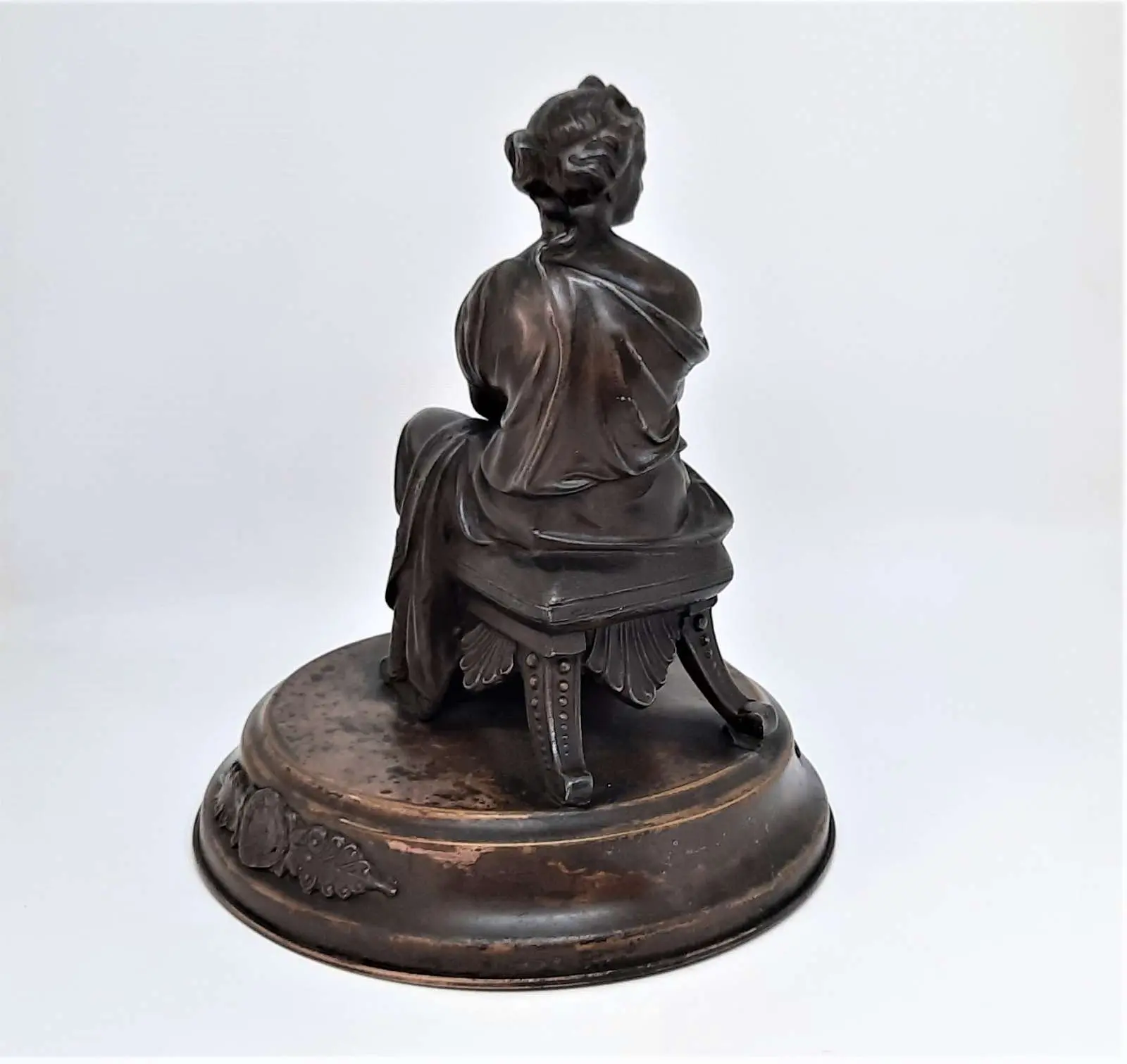 Figura siedzącej kobiety w stroju antycznym z wieńcem laurowym w dłoniach